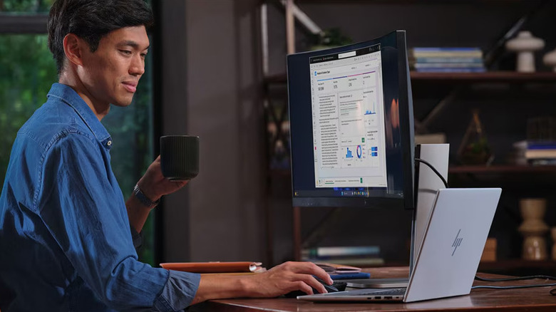 A man using an HP laptop at his home workstation