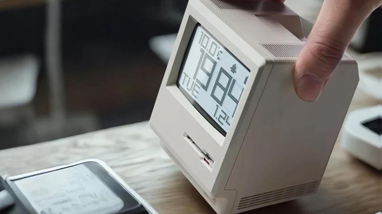 A hand setting the RayCue Maclock WB-8 retro alarm clock on a desk