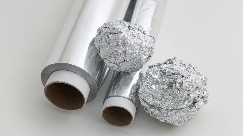 Two rolls of aluminum foil and two crumpled balls of foil