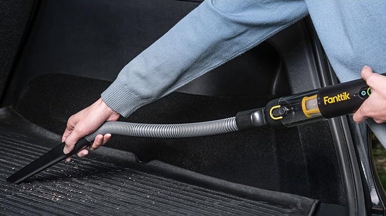 A person using the Fanttik Slim V10 Apex Cordless Car Vacuum to clean their car