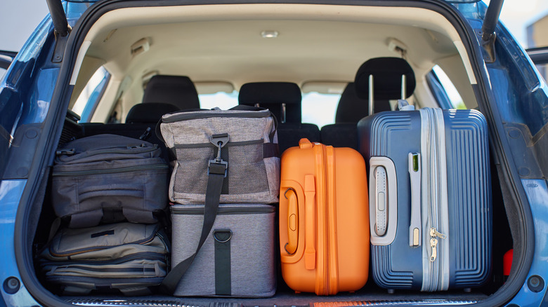 A full car trunk packed with suitcases, backpacks and bags
