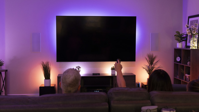 Smart lighting backlights a TV and plants as part of a home theater setup