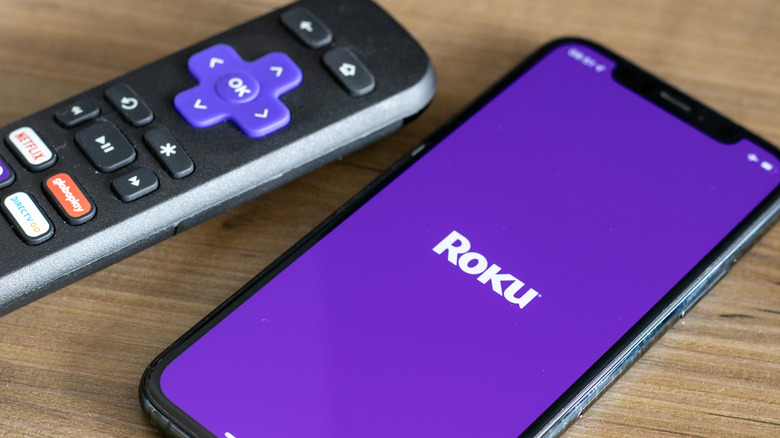 Smartphone with Roku app opening and the roku remote next to it