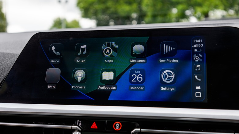 An infotainment system showing CarPlay with the iOS 26 Liquid Glass UI