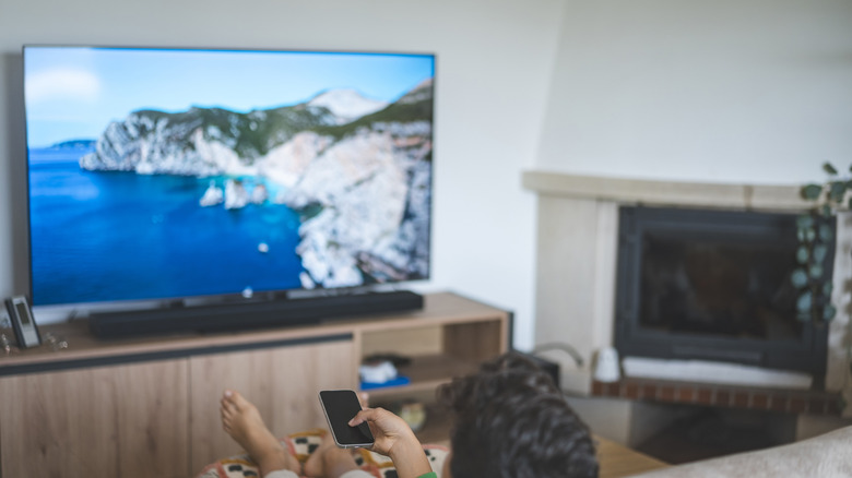 person using smartphone as controller for their smart TV in a living room environment