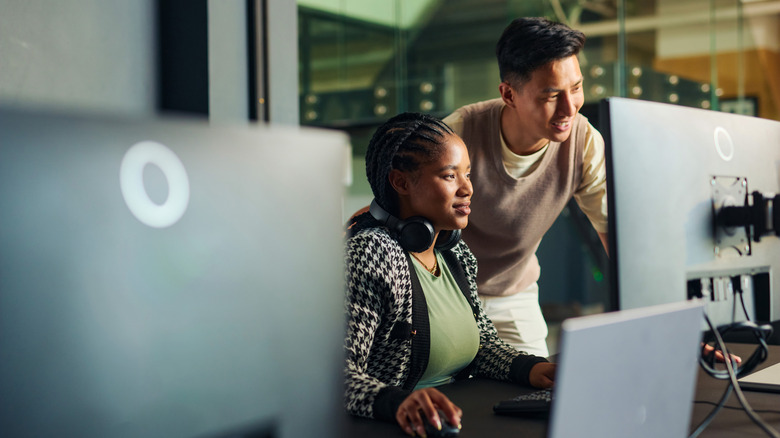 Two young people looking at computer monitor and smiling