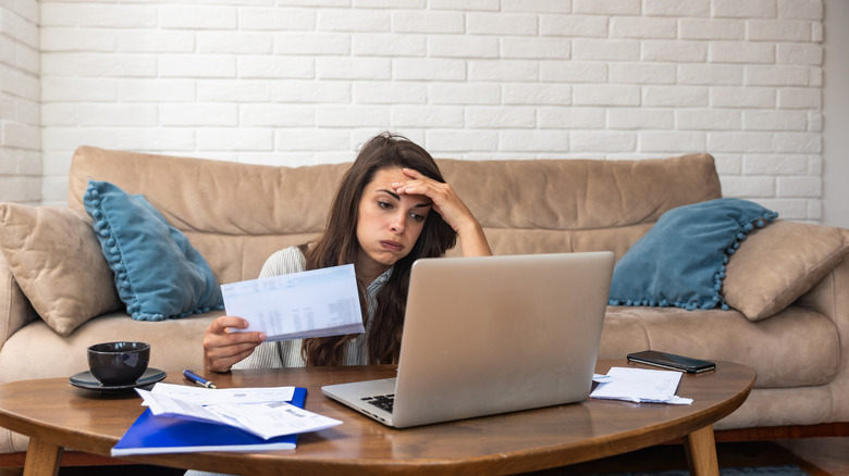 Young woman at computer stressed over bills