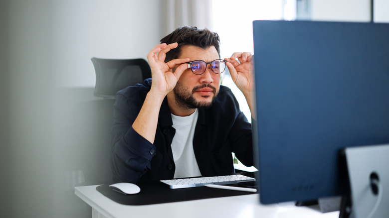 Man squinting at computer screen
