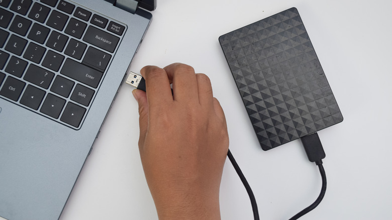 Someone connecting an external drive to a laptop