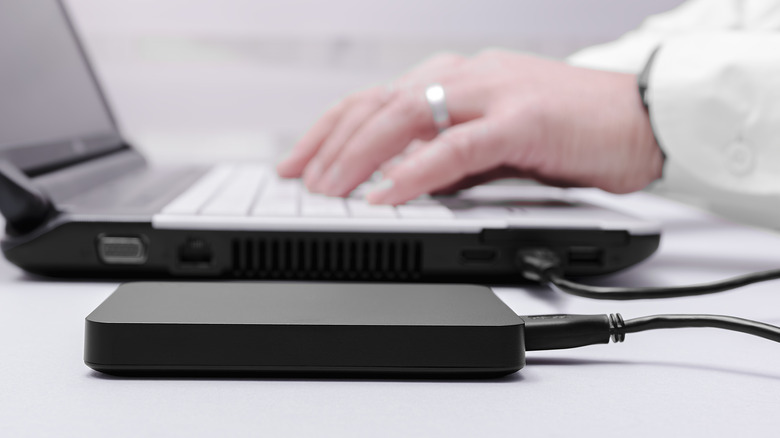 Someone using a laptop with an external drive connected to it