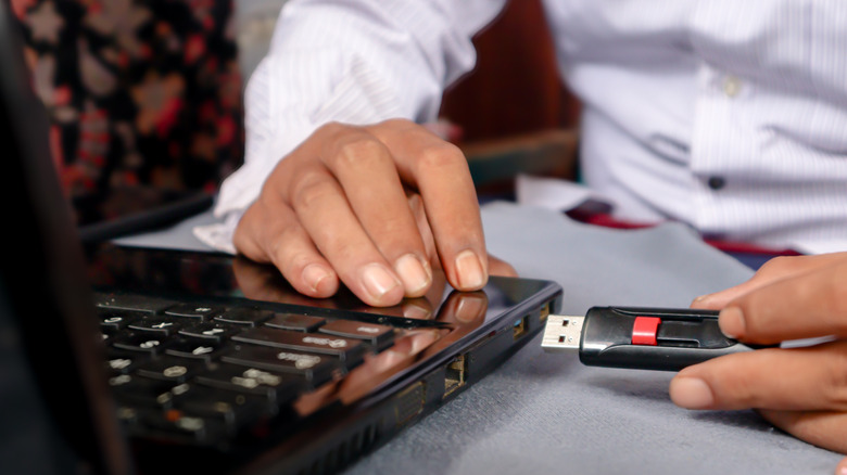 a person plugging a usb drive into a laptop