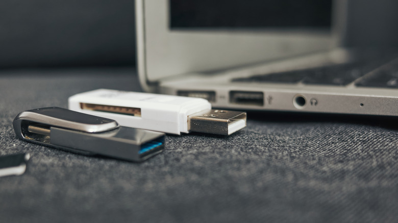 multiple USB drives next to a laptop