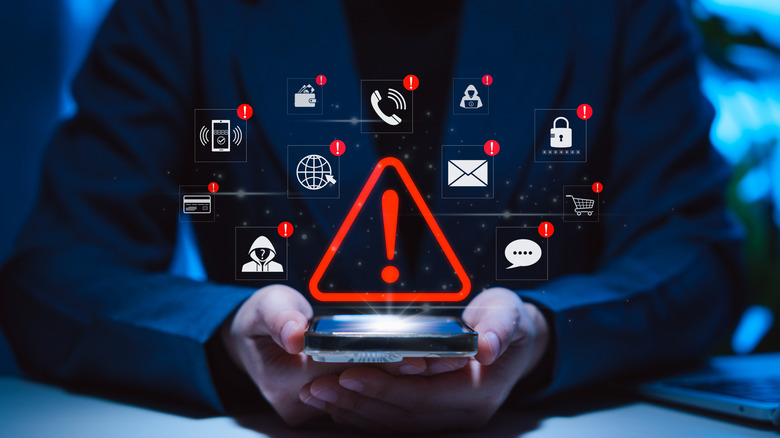 An individual in black holds a smartphone in their cupped hands, above the phone is several computer generated graphics of smartphone icons that have notification warnings next to them