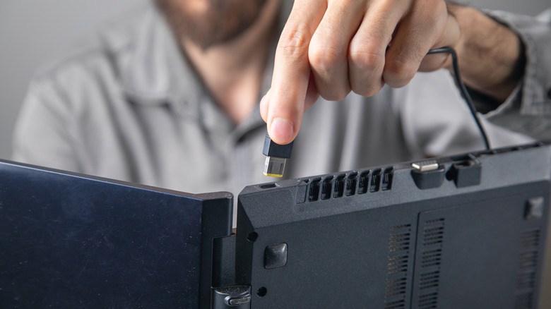 Person inserting charging cord into laptop