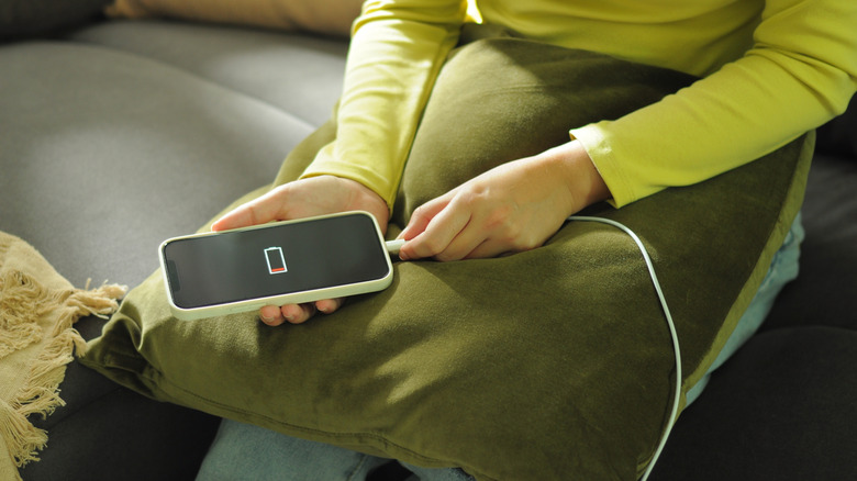 Close-up of a person holding a phone charger cable into a phone's charging port