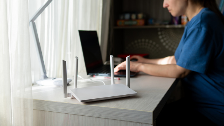 A person working at a desk next to a white router