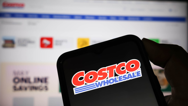 Phone showing a Costco logo against a computer screen.