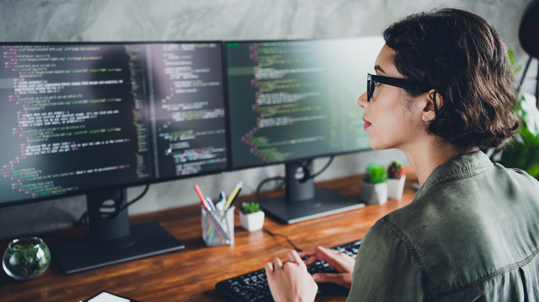 A person working with two monitors in front of them at a desk