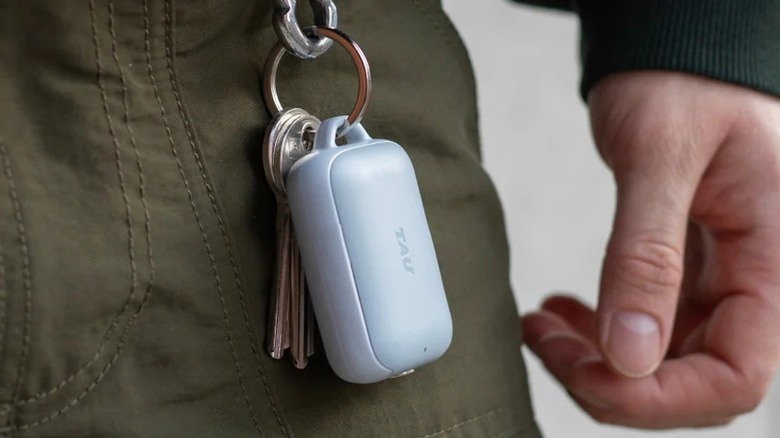 TAU 2 portable charger attached to a keychain on a person's pants.