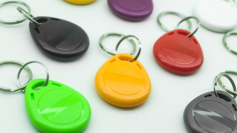 Colorful NFC keychain tags with metal rings scattered on a white surface.