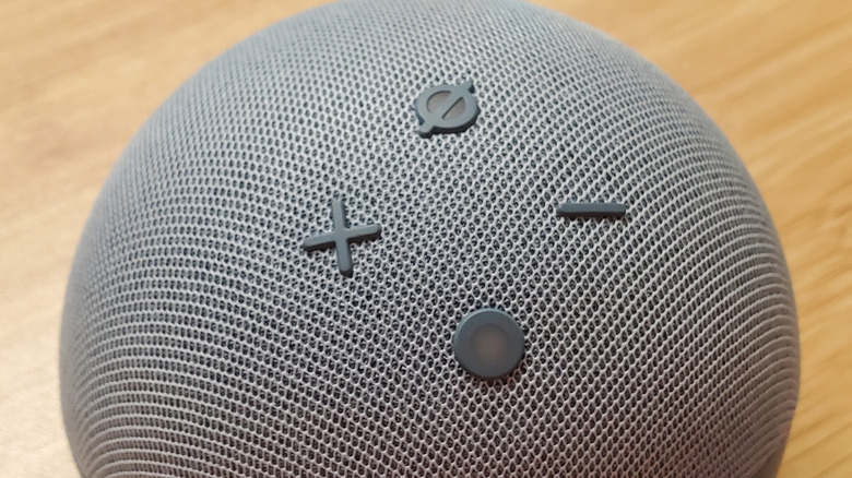 A close-up of an gray Amazon Echo Dot on a wooden surface.