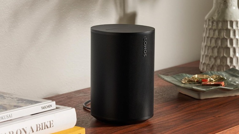 The Sonos Era 100 on a wooden table.