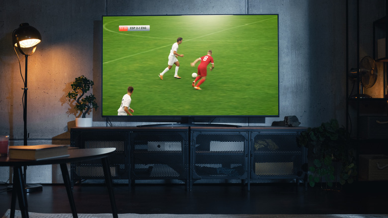 A soccer match playing on a TV in the center of a dimmed room