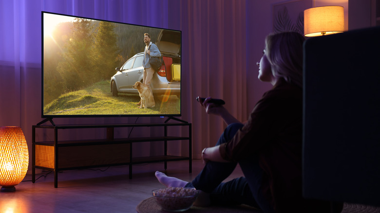 A person sitting watching TV in a dimmed room