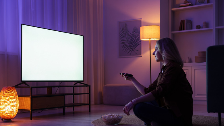 a woman watching TV with a blank white screen