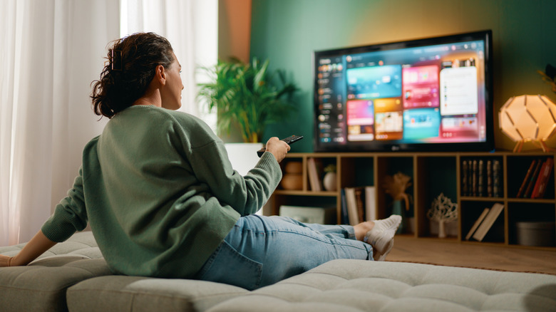 Person using a remote to browse a smart TV menu in a cozy living room.
