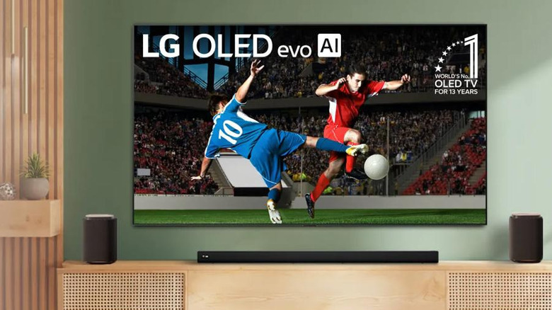 LG OLED evo AI TV showing a soccer match in a living room setup with a soundbar and speakers.