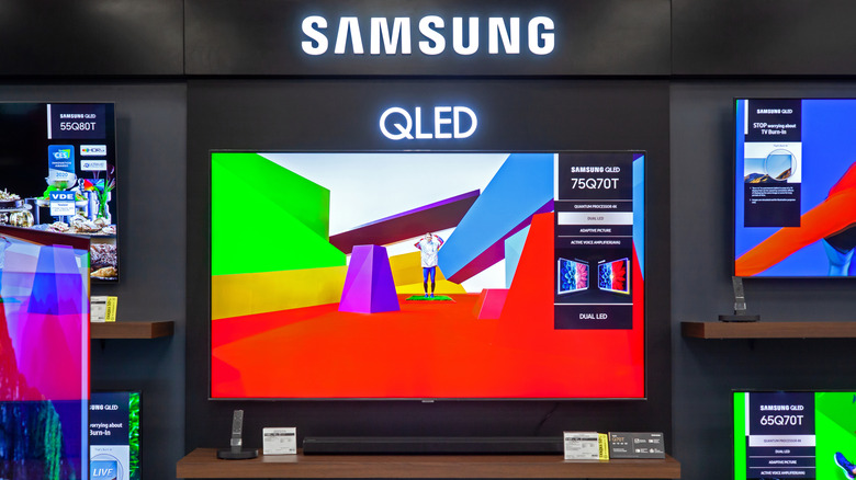 Samsung QLED TV displayed in an electronics store with colorful screen demos.