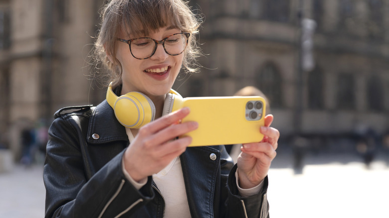 A young woman uses her smartphone's cameras to shoot photos.