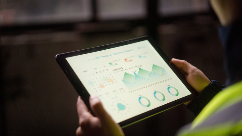 worker using a tablet with graphs visible on screen