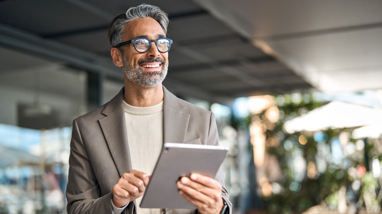 A man smiling while holding a tablet.