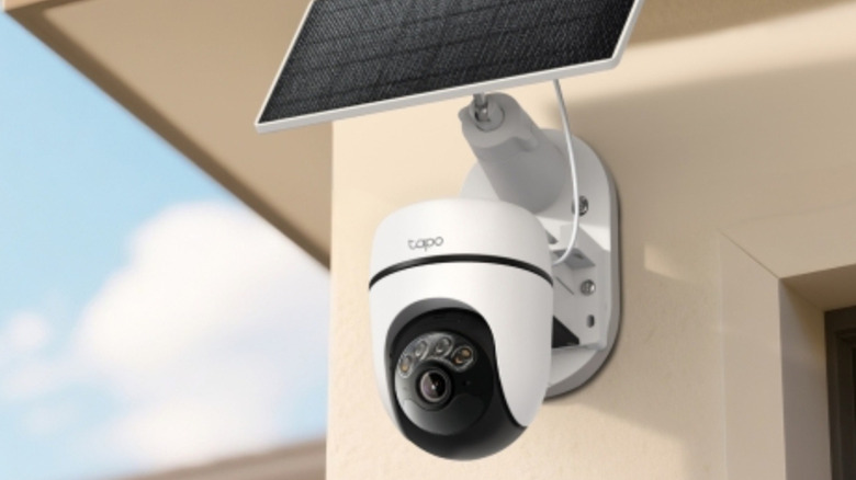 A Tapo outdoor security camera mounted to the exterior of a home, below a connected solar panel.