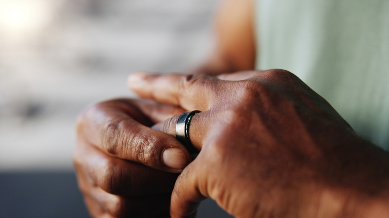 A man's hands putting on a smart ring.