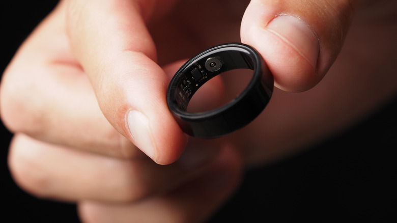A hand holding a smart ring close up.