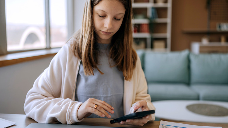 A young woman manipulating a phone while wearing a smart ring.