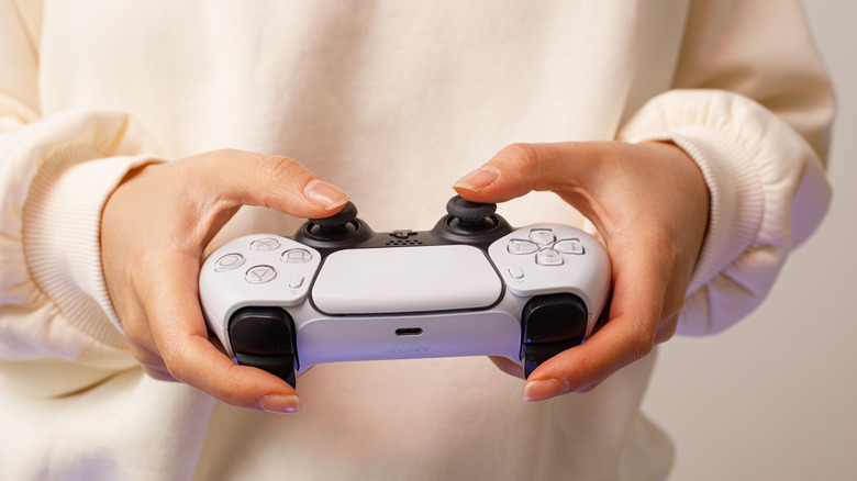 Close up of hands holding a PlayStation 5 controller