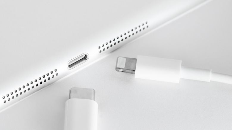 A Lightning cable and USB-C cable placed near the charge port of what looks like an iPad.