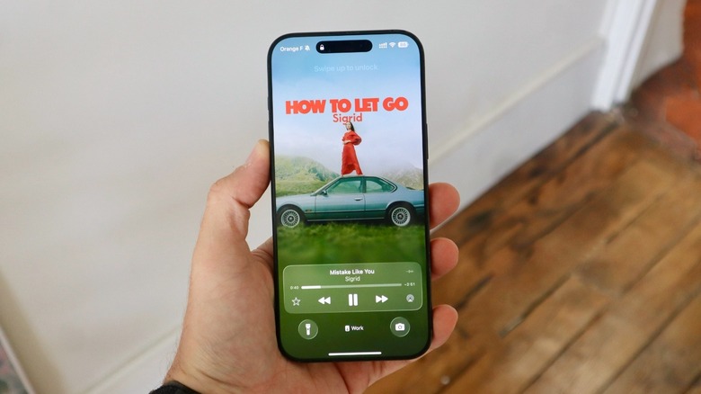 A hand holding an iPhone displaying its Lock Screen