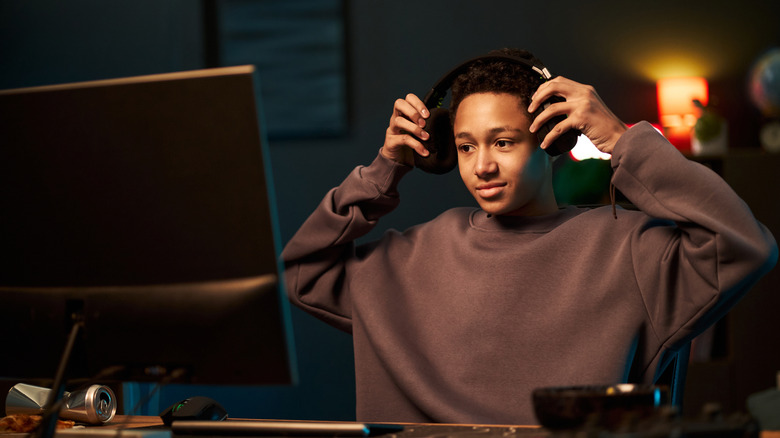 Young boy with headphones sitting at desk and preparing to use computer