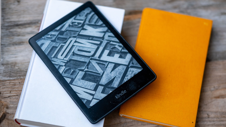 A Kindle device placed alongside hardcover books