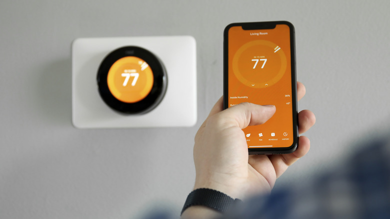 A person adjusting the temperature setting on a smart thermostat using a phone app