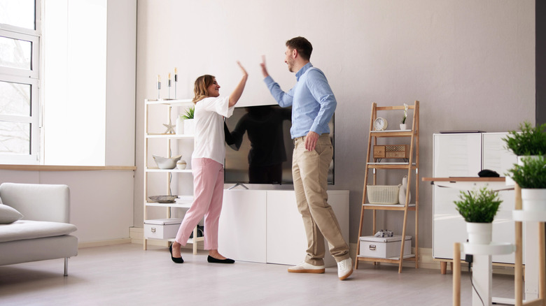 A couple high-fiving over the placement of a TV