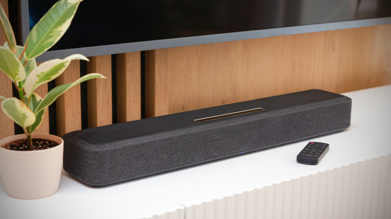 A soundbar placed on top of an entertainment center with a wall-mounted TV hanging above it