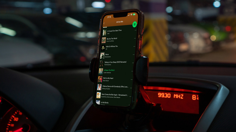 close-up of spotify app open on a smartphone on a car phone holder