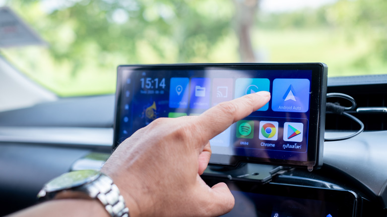 hand reaching for infotainment system with Android auto icon visible