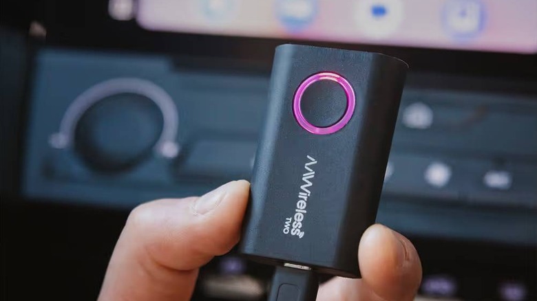 close-up of fingers holding onto AA Wireless android auto adapter